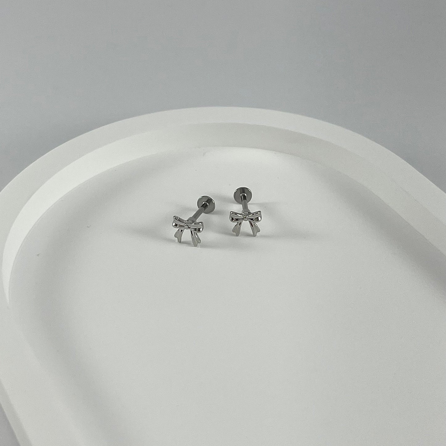 Small bow flatback earrings on a white surface.