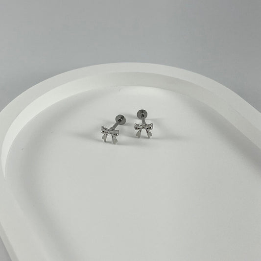 Small bow flatback earrings on a white surface.