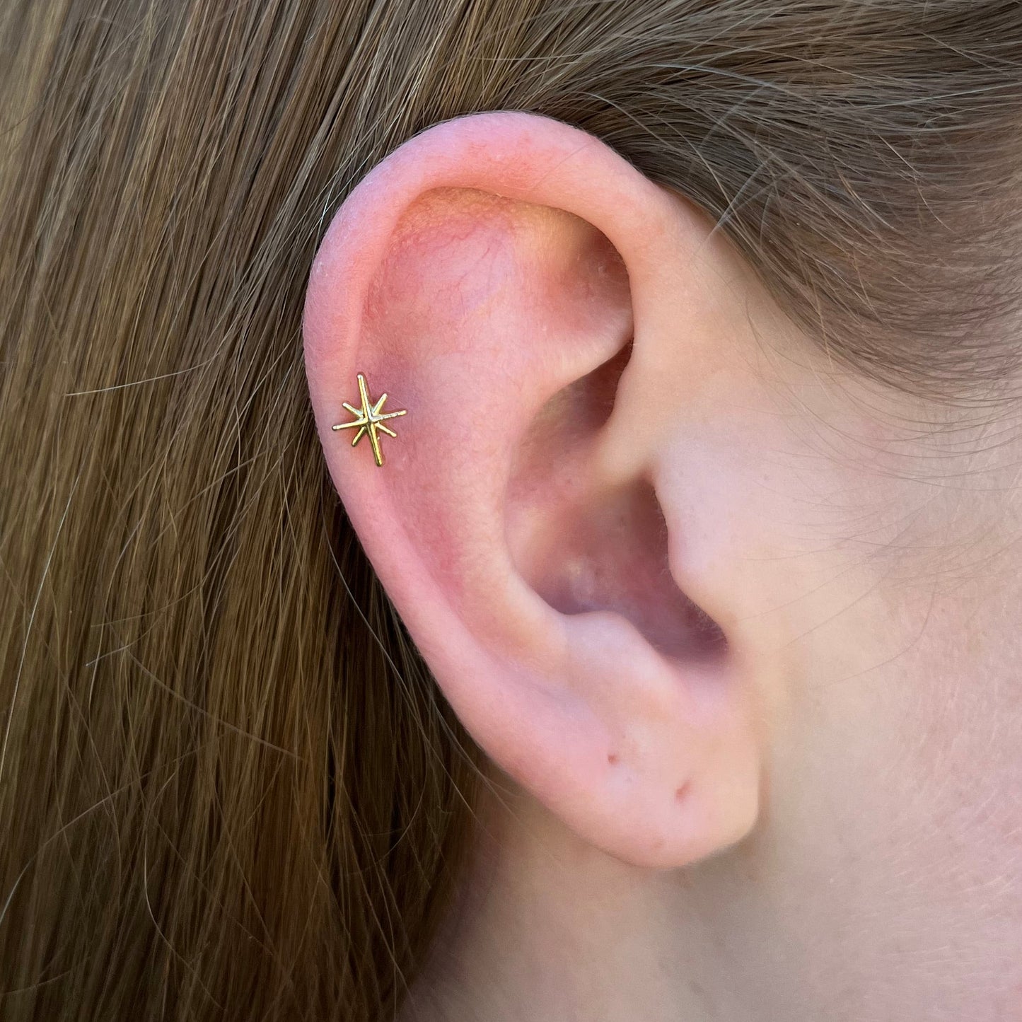 Picture of a star flatback earring in gold. 