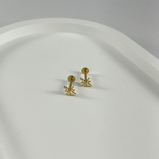 Gold star-shaped flatback earrings on a white plate.